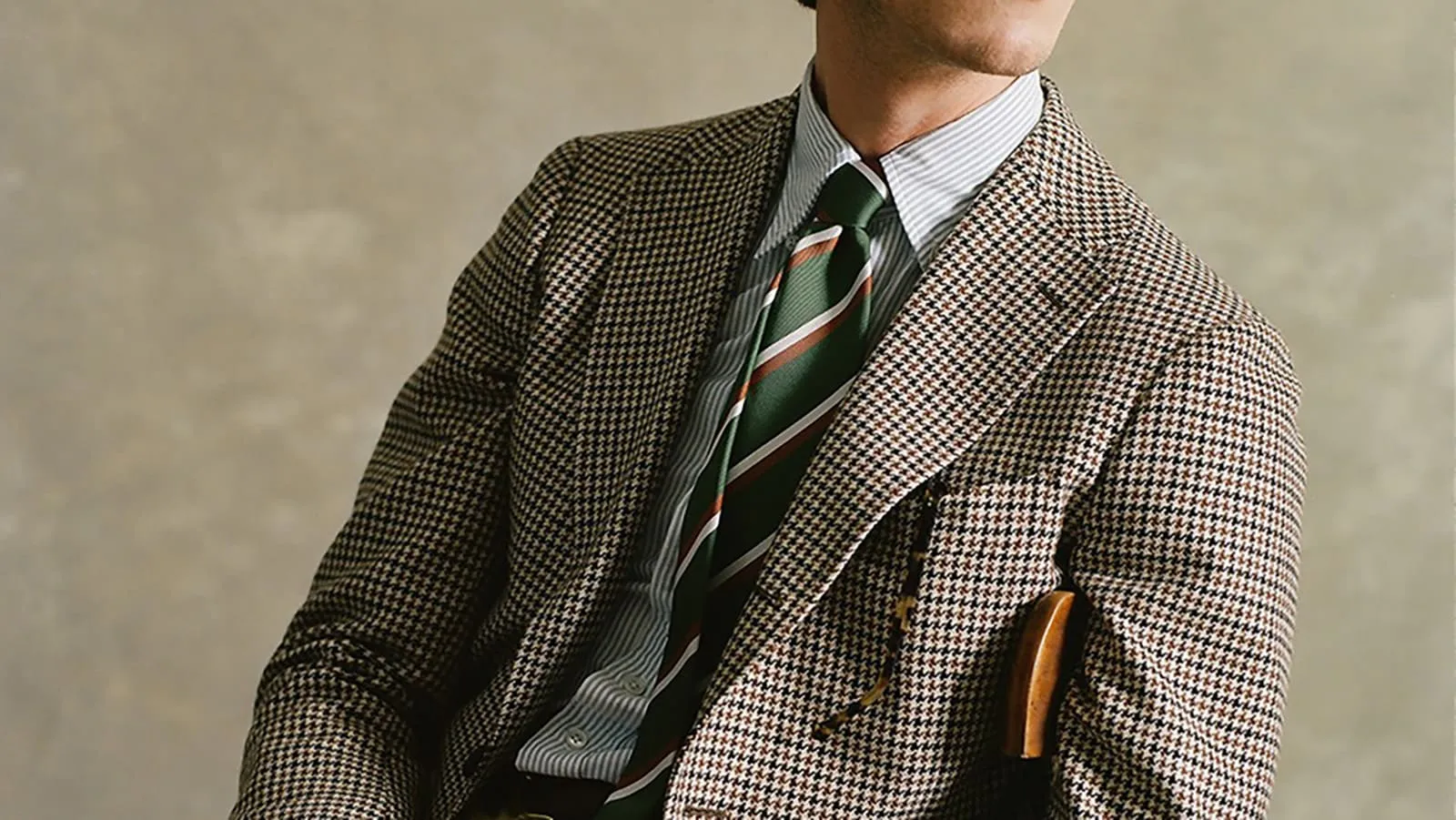 チェック柄のスーツと緑のストライプネクタイを着用した男性の半身像。エレガントなビジネススタイル。